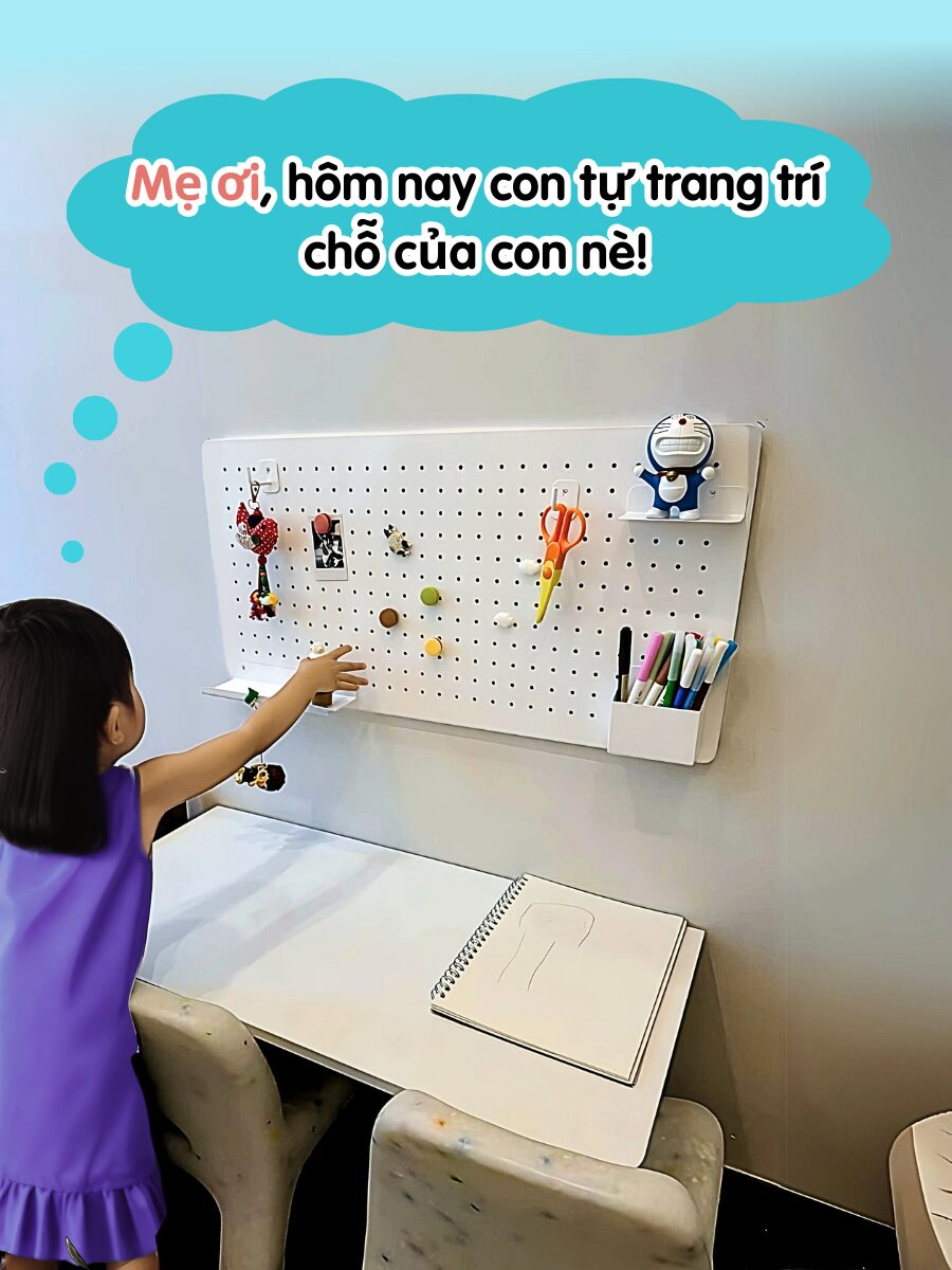 B&eacute; g&aacute;i mặc v&aacute;y t&iacute;m đang treo đồ chơi l&ecirc;n bảng pegboard trắng trong g&oacute;c học tập